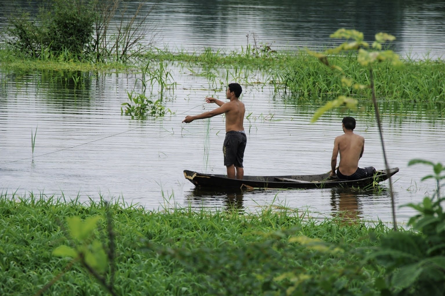 Fisherman casting a net from a canoe
